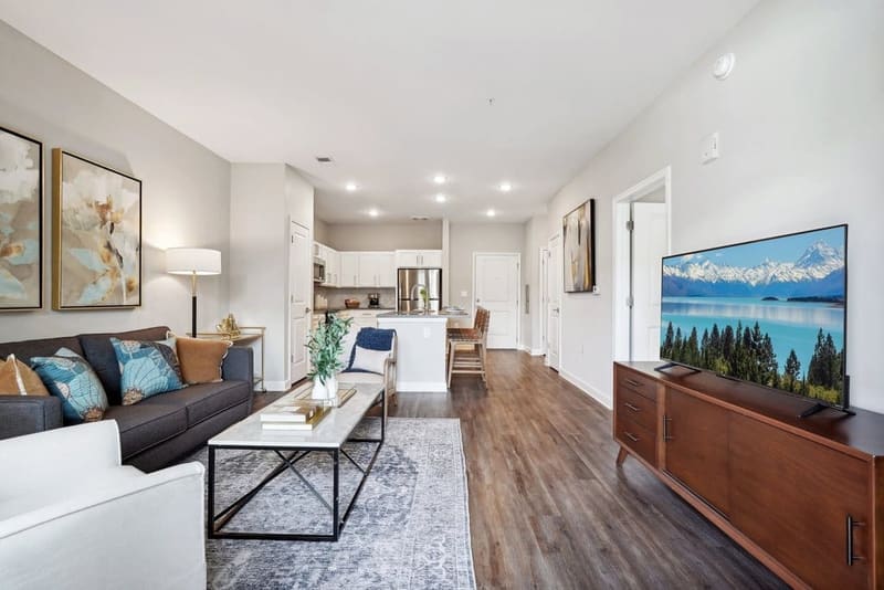 Living room of an apartment home at The Chateau by Highlands, opening onto the kitchen and island